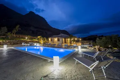 a swimming pool with chairs and a house at Villa Gea in Castellammare del Golfo