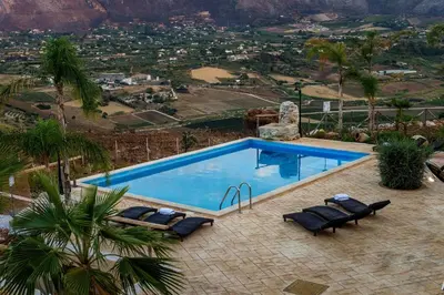 a swimming pool with chairs and a view of a city at Villa Thalia in Castellammare del Golfo