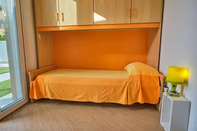a small bedroom with a bed with an orange blanket at Villa Sicilia in Lascari