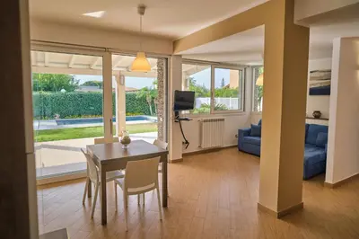 a living room with a dining room table and a tv at Villa Sicilia in Lascari