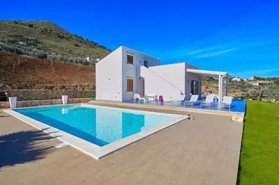 a villa with a swimming pool in front of a house at VILLA ANANDA in Scopello