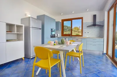 a kitchen with a table and yellow chairs at VILLA ANANDA in Scopello