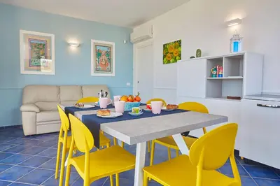a kitchen and dining room with a table and yellow chairs at VILLA ANANDA in Scopello