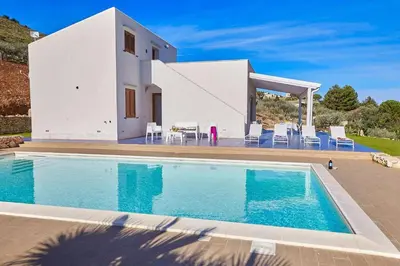 a villa with a swimming pool in front of a house at VILLA ANANDA in Scopello