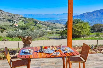 a wooden table with food on it with two chairs at Villa Montemar in Balata di Baida