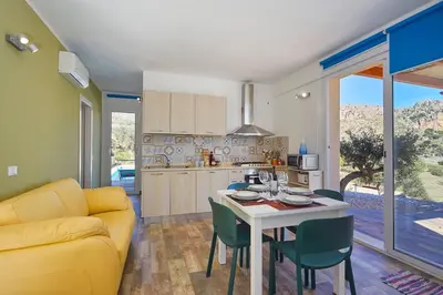 a kitchen and living room with a yellow couch and a table at Villa Montemar in Balata di Baida