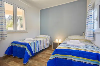 a bedroom with two beds and a window at Villa Montemar in Balata di Baida