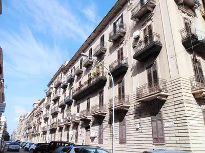 a large building with balconies and cars parked on a street at Le vie del Centro in Palermo