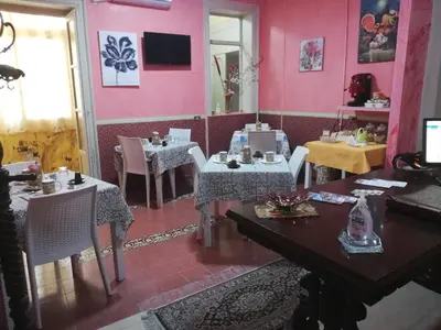 a restaurant with tables and chairs and pink walls at B&B Orchidea in Palermo