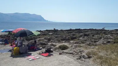 a group of people sitting on a beach with umbrellas at Casa Vacanze Trinacria in Isola delle Femmine