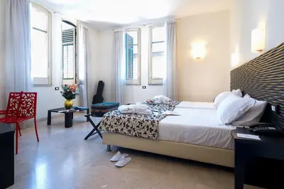 a bedroom with a bed and a table and windows at Hotel Garibaldi in Palermo