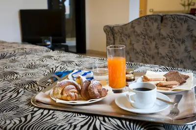 a tray of breakfast foods and orange juice on a bed at Hotel Garibaldi in Palermo