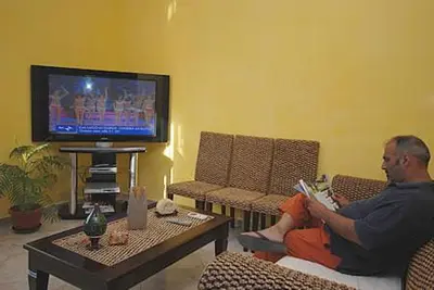 a man sitting on a couch reading a book in front of a tv at Hotel Altamarea in San Vito lo Capo