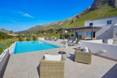 a swimming pool with two chairs and a house at Villa Biancolilla in Castellammare del Golfo