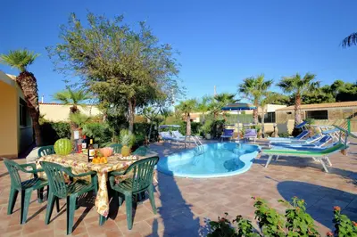 a patio with a table and chairs and a pool at Villa Minoa con piscina in San Vito lo Capo
