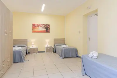 a room with three beds and a painting on the wall at Casa per Ferie Don Orione Palermo in Palermo