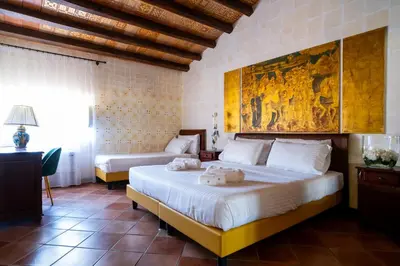 a bedroom with two beds and a painting on the wall at Villa Vittoria Hotel in Alcamo