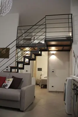 a living room with a couch and a spiral staircase at Mamiani Suite in Castellammare del Golfo