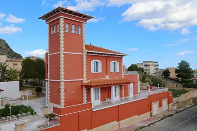 an orange building with a clock tower on a street at Villa Edera Rental Room in Santa Flavia