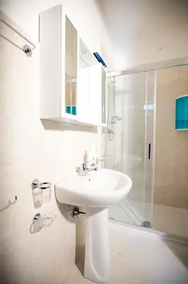 a white bathroom with a sink and a shower at Appartamenti Duchessa in Castellammare del Golfo