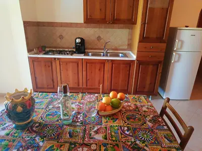 a kitchen with a table with a bowl of fruit on it at Villette di Scopello - Casa Vacanze in Scopello