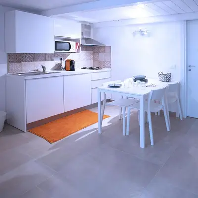 a white kitchen with a white table and chairs at SpAsimoH-2 in Palermo