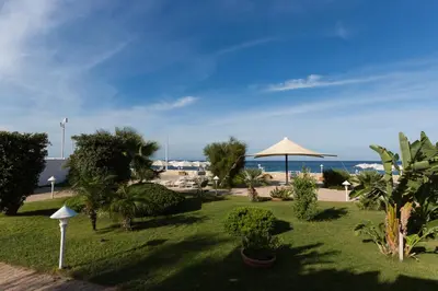 a resort with a lawn with trees and a beach at La Marsa Vacances in Mondello