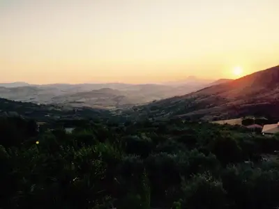 a view of the sun setting over a valley at Villa in Alia with Pool & Olive Views in Alia