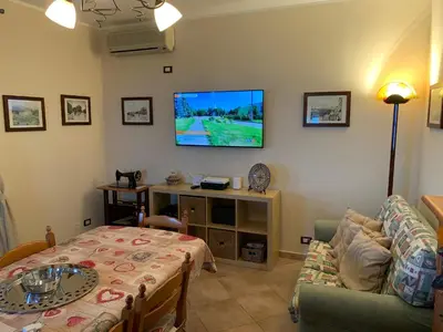 a living room with a couch and a tv on the wall at Villa Ibiscus in Mandra Capreria