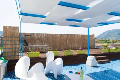 a patio with white chairs and an umbrella at Villa con piscina Alcamo Marina in Alcamo