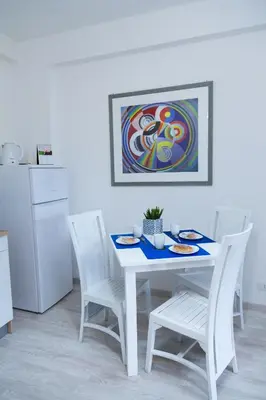 a white kitchen with a white table and chairs at MiKlod Apartments in Palermo