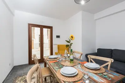 a dining room with a table and a couch at Finisterre in San Vito lo Capo