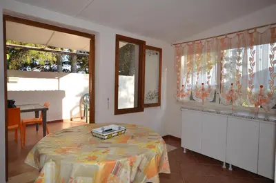 a room with a bed and a table and windows at Villetta SanVito - Sunrise & Sunset in San Vito lo Capo