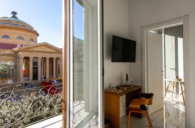 a room with a balcony with a view of a building at Palazzo Sovrana Serviced Luxury Apartments in Palermo