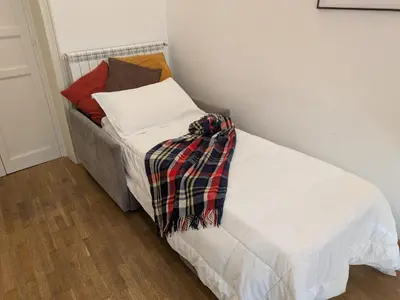 a bed with white sheets and a plaid blanket at B&B del Parlamento in Palermo
