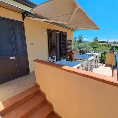 a balcony with a table and chairs and an umbrella at Sunrise in Lascari