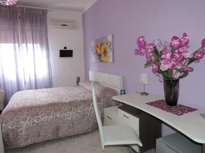 a bedroom with a bed and a table with a vase of flowers at Bed and Breakfast Il Girasole in Mondello