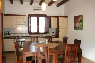 a kitchen with a wooden dining room table and chairs at Villa Giardino Paradiso Cefalù con 13 posti letto e piscina riscaldata in Cefalù