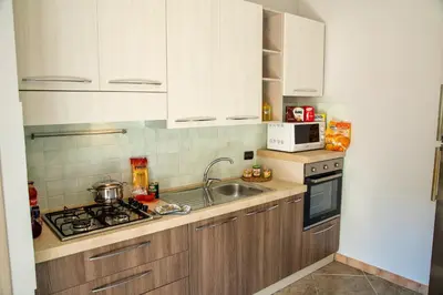 a kitchen with white cabinets and a sink and a stove at Sicilia Case Vacanze in Balestrate