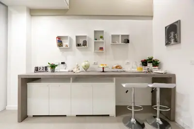 a kitchen with white cabinets and a counter with stools at Maison Cutò in Palermo