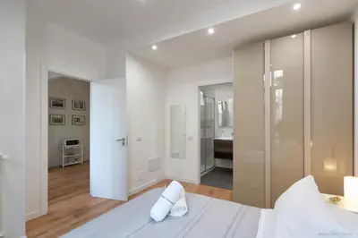 a white bedroom with a white bed and a bathroom at Maison Cutò in Palermo