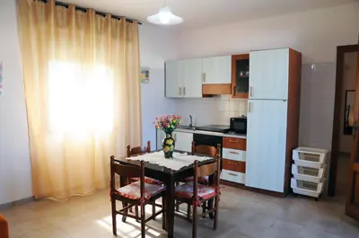a kitchen with a table with chairs and a refrigerator at Katia appartamenti in San Vito lo Capo