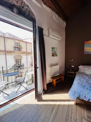 a bedroom with a balcony with a bed and a sliding glass door at Kasa Kala Rooms & Apartments in Palermo