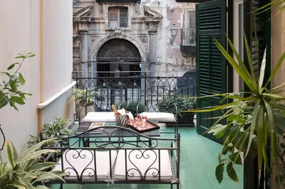 a balcony with a table and chairs in front of a building at Palazzo Arone dei Baroni di Valentino in Palermo