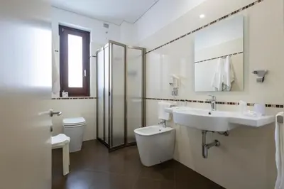 a bathroom with a sink and a toilet and a mirror at Alaba Hotel in San Vito lo Capo