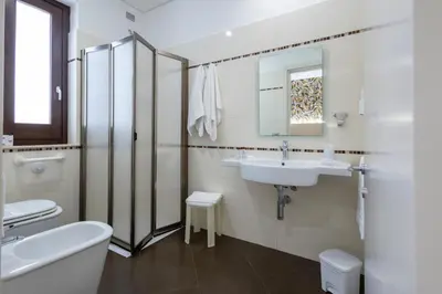 a white bathroom with a sink and a toilet at Alaba Hotel in San Vito lo Capo