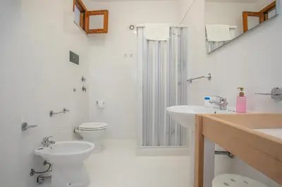 a white bathroom with a toilet and a sink at Casa BabbaLuciana in Mondello
