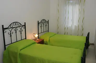 two beds in a room with green sheets at case vacanze Rosy in San Vito lo Capo