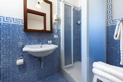a blue tiled bathroom with a sink and a shower at La Meridiana Hotel in San Vito lo Capo