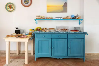 a blue cabinet with food on it next to two tables at La Meridiana Hotel in San Vito lo Capo